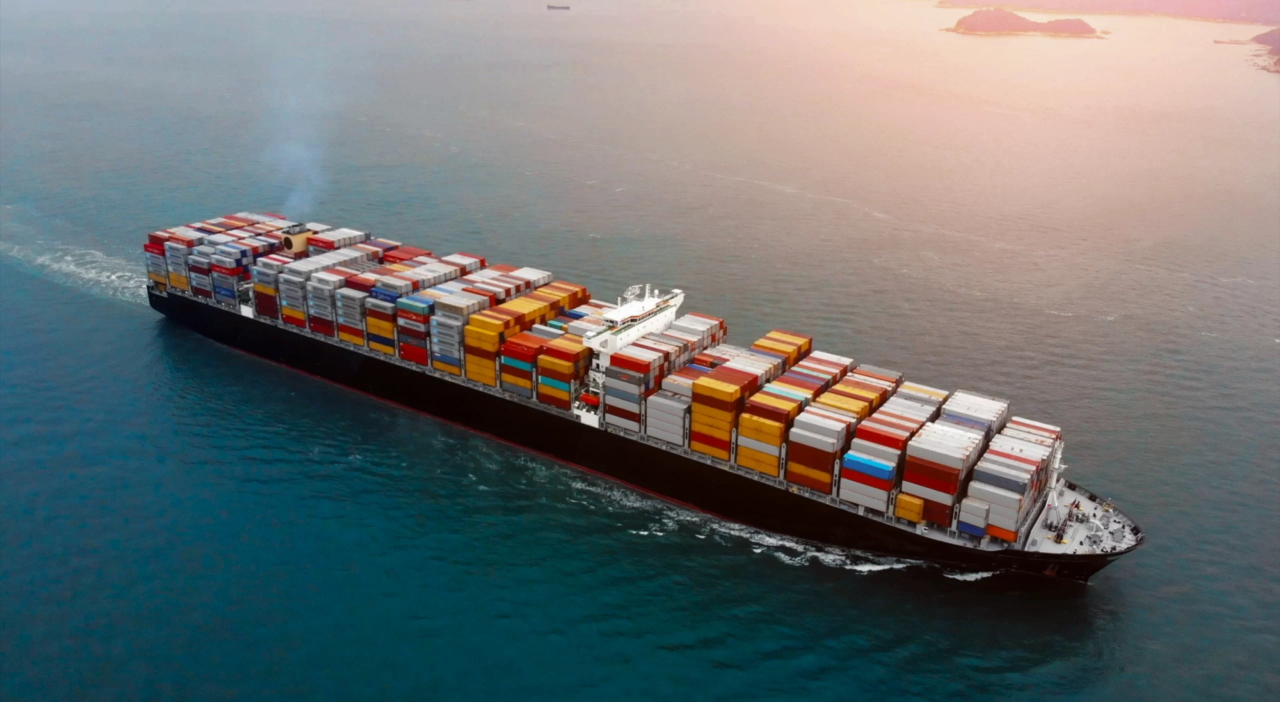 An aerial view of a massive container ship navigating the ocean for sea freight transportation.