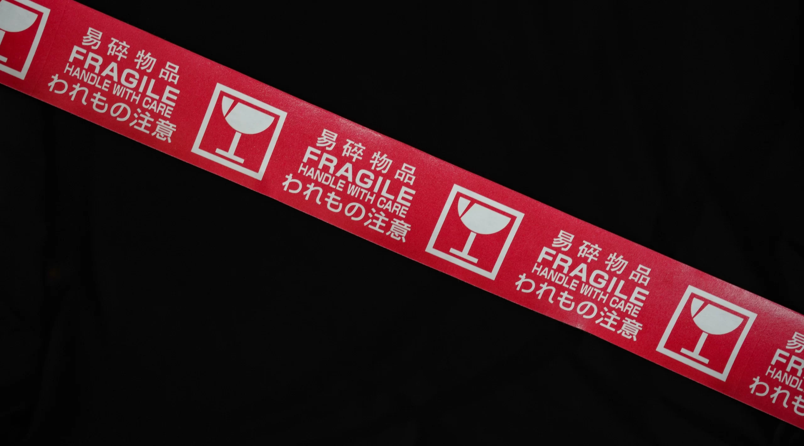 A red ribbon with the words fragile on it, indicating the handling of delicate items.